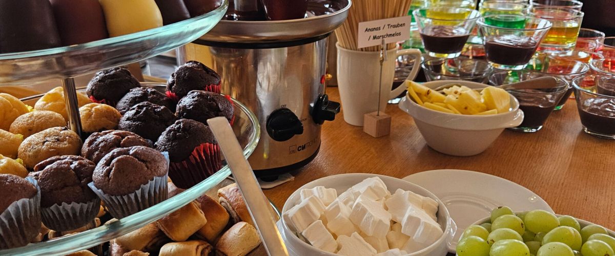 Ein reichhaltiges Buffet im Strandcafé Sturmeck bietet Muffins, Waffeln und Früchte neben einem Schokoladenbrunnen.