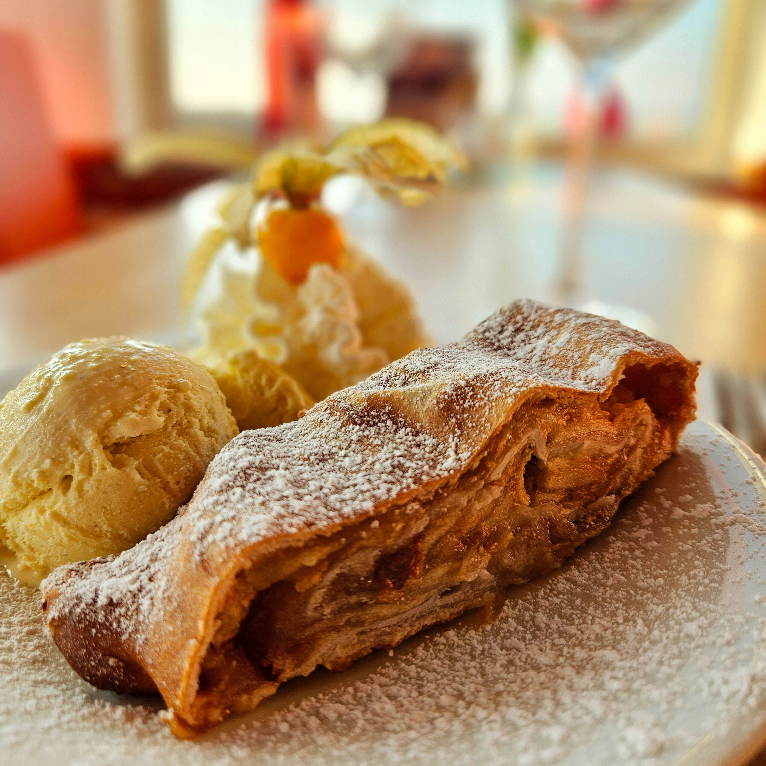 Ein köstlicher Apfelstrudel mit Vanilleeis und Sahne wird im gemütlichen Strandcafé serviert.