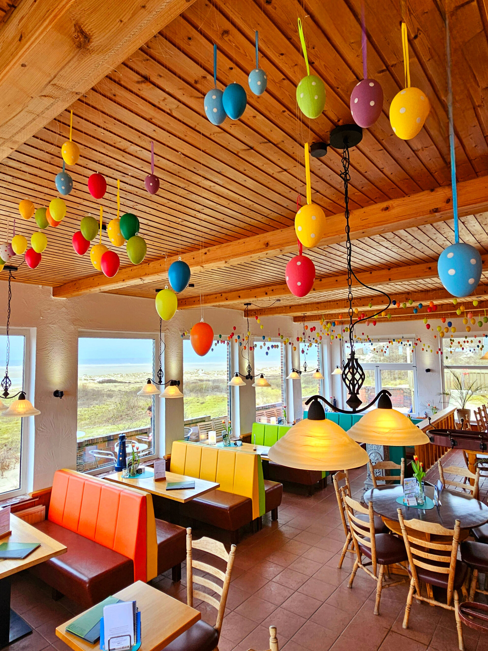 Bunt dekoriertes Strandcafé Sturmeck mit fröhlichen Ostereiern und Meerblick, ideal für entspannte Momente.