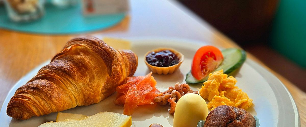 Ein reichhaltiges Frühstück mit Croissant, Käse, Lachs und mehr wird im Strandcafé Sturmeck serviert.