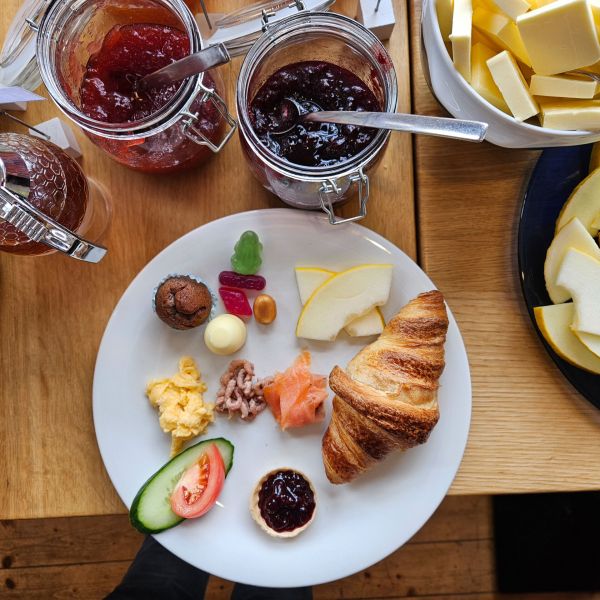Ein reichhaltiges Frühstück im Strandcafé Sturmeck mit Croissant, Lachs und Marmelade auf einem weißen Teller.