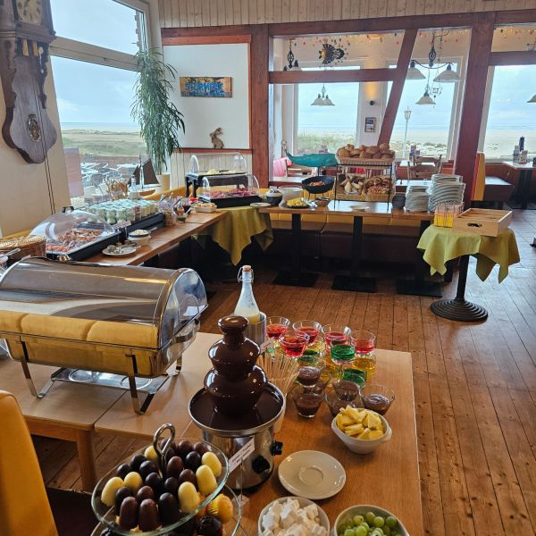 Ein reichhaltiges Frühstücksbuffet mit Schokoladenbrunnen und Meerblick lädt im Strandcafé zu einem genussvollen Start ein.